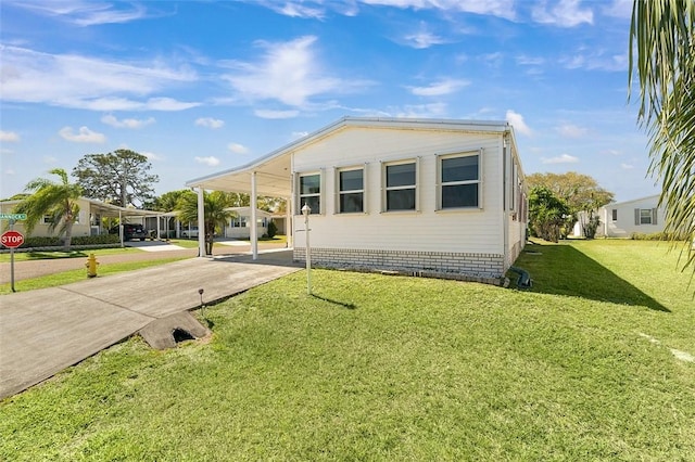 manufactured / mobile home with driveway, a front lawn, and an attached carport