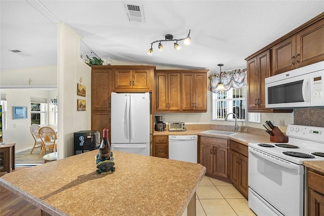 kitchen featuring white appliances, light tile patterned floors, visible vents, brown cabinets, and a sink