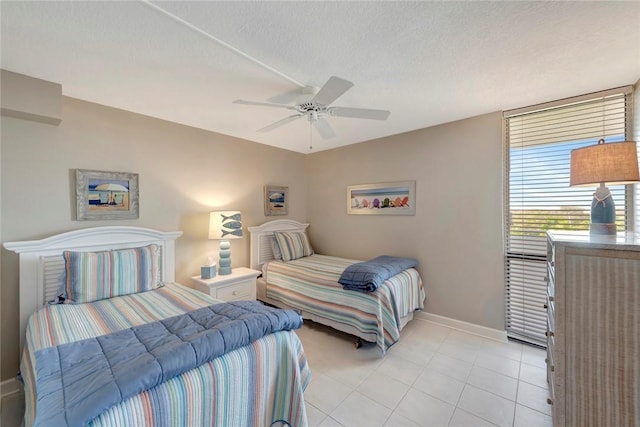 bedroom with light tile patterned floors, baseboards, a ceiling fan, and a textured ceiling