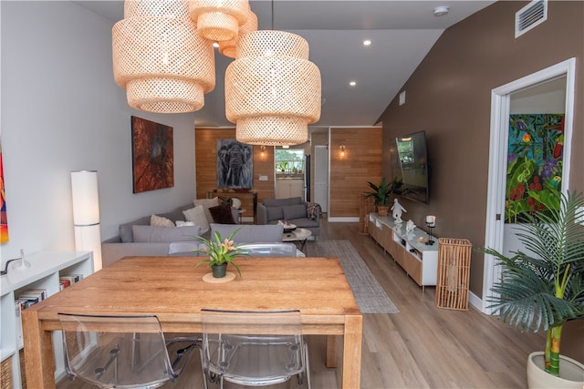 dining space featuring light wood-type flooring and vaulted ceiling