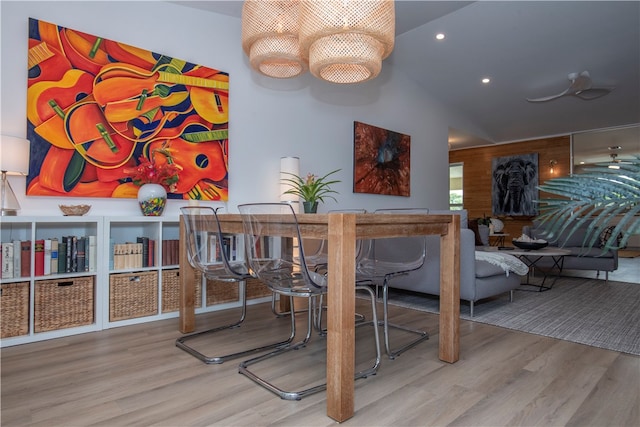 dining space with ceiling fan with notable chandelier, wood-type flooring, and vaulted ceiling