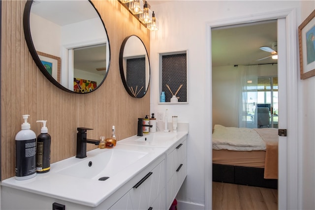 bathroom with wooden walls, hardwood / wood-style flooring, ceiling fan, and vanity