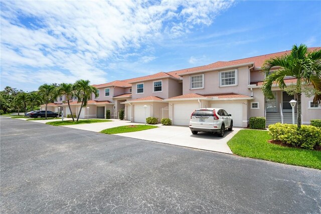 255 Grand Royale Cir Unit 204, Vero Beach, FL 32962 - view of property featuring stucco siding, driveway, an attached garage, and a residential view