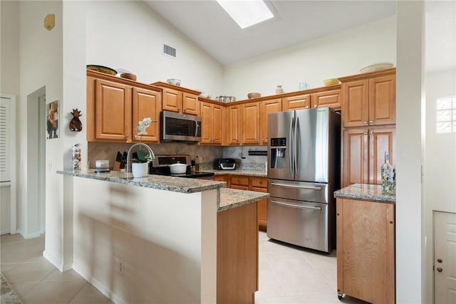 255 Grand Royale Cir Unit 204, Vero Beach, FL 32962 - kitchen with appliances with stainless steel finishes, high vaulted ceiling, light tile patterned floors, a peninsula, and light stone counters