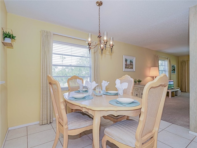 dining area featuring a textured ceiling, a notable chandelier, a healthy amount of sunlight, and light tile patterned floors