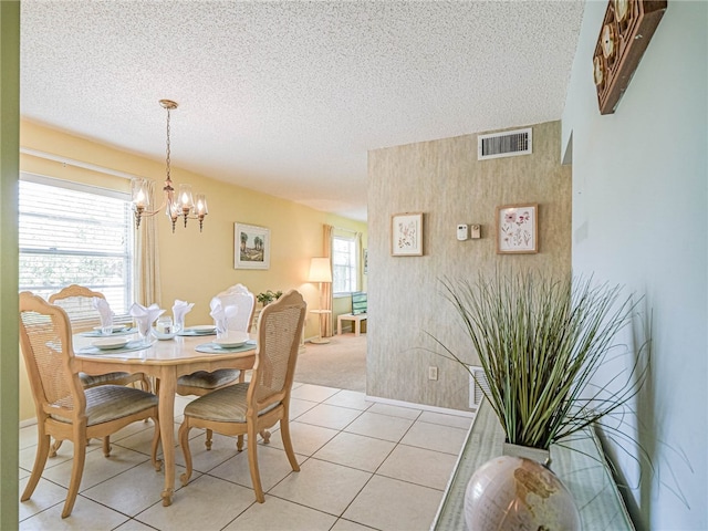 tiled dining space featuring an inviting chandelier and a textured ceiling