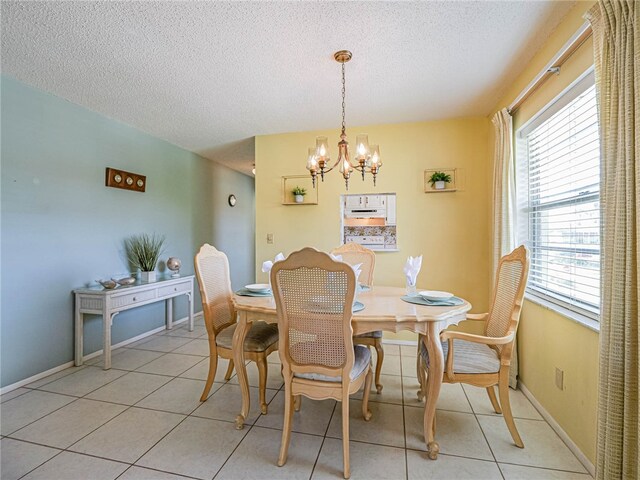 dining area featuring a textured ceiling, a chandelier, and light tile patterned flooring