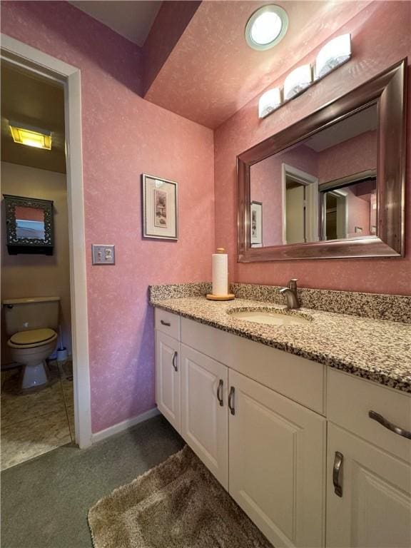 bathroom with vanity, baseboards, and toilet