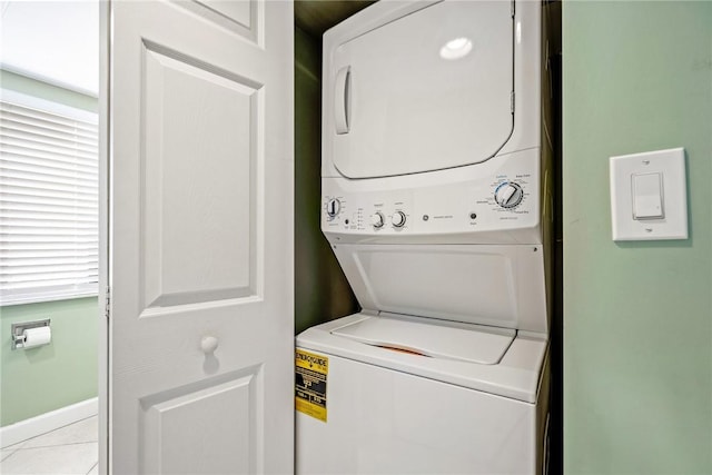 washroom with light tile patterned floors, stacked washer / dryer, and a healthy amount of sunlight