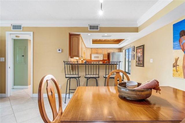 dining area with a raised ceiling, ornamental molding, and light tile patterned floors