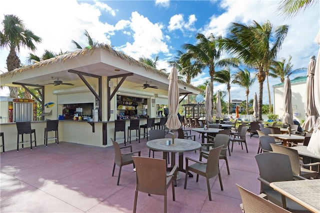 view of patio with ceiling fan and a bar