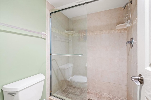 bathroom featuring a shower with door and toilet