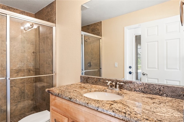 bathroom with vanity, a shower with shower door, and toilet