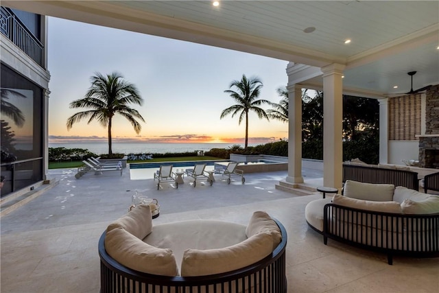 patio terrace at dusk featuring an outdoor living space and a water view