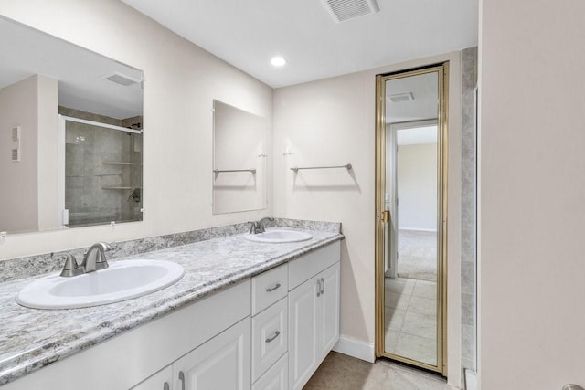 1166 6th Ave Unit 19C, Vero Beach, FL 32960 - bathroom featuring double vanity, a shower with shower door, tile patterned flooring, and baseboards