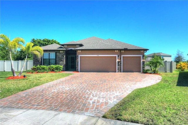 prairie-style home featuring stucco siding, a front yard, a garage, and fence