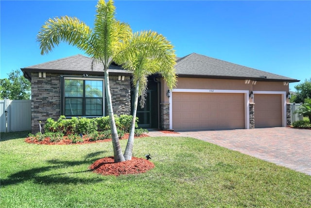 view of front of home featuring a front lawn, fence, stucco siding, decorative driveway, and a garage