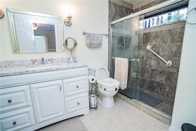 bathroom featuring toilet, tile patterned floors, a shower with shower door, and vanity