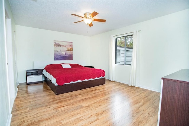 bedroom featuring ceiling fan, a textured ceiling, and light hardwood / wood-style flooring