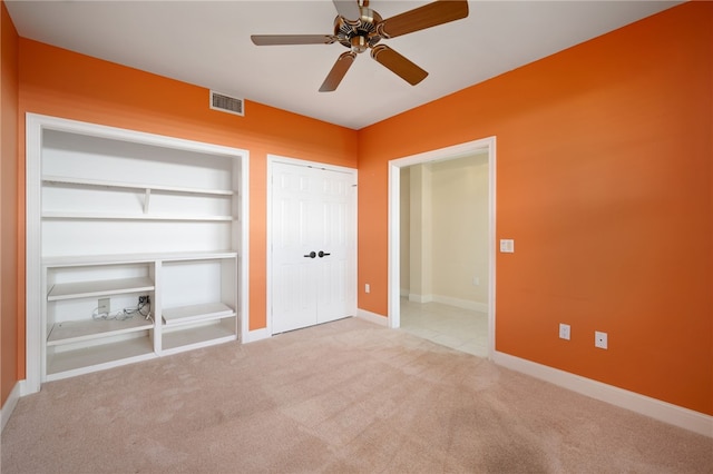 unfurnished bedroom featuring ceiling fan, light colored carpet, and a closet