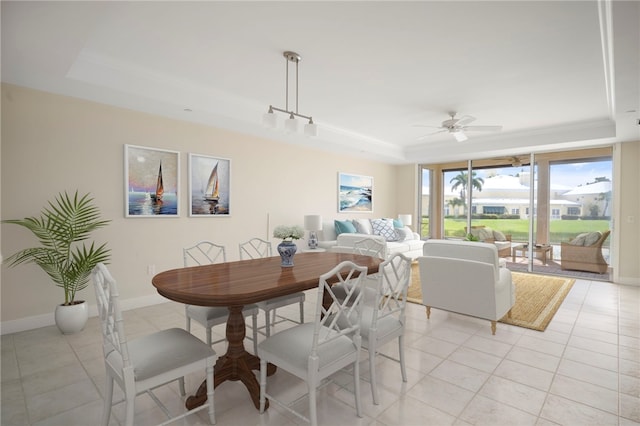 tiled dining area with a tray ceiling and ceiling fan