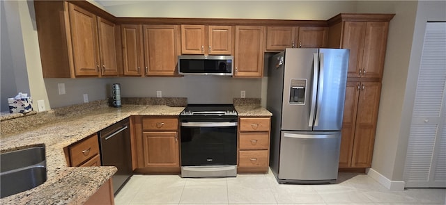 kitchen with light stone countertops, light tile patterned floors, and stainless steel appliances