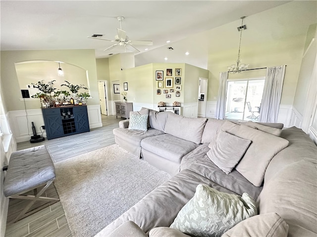 living room featuring ceiling fan with notable chandelier, light hardwood / wood-style flooring, and high vaulted ceiling