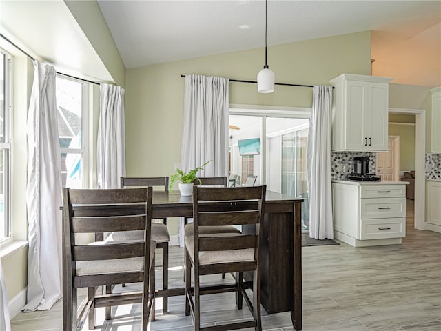 dining area featuring light wood-type flooring and lofted ceiling