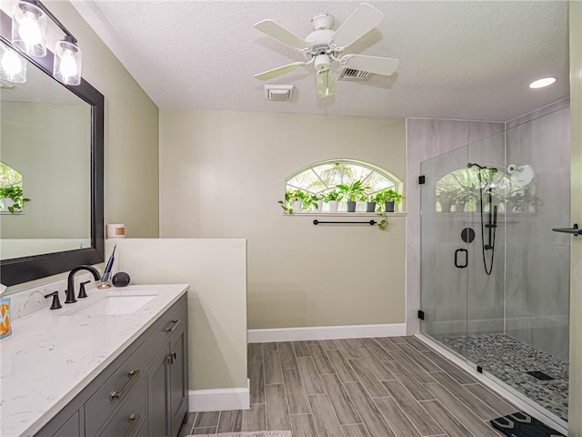 bathroom with a shower with door, a textured ceiling, hardwood / wood-style flooring, vanity, and ceiling fan