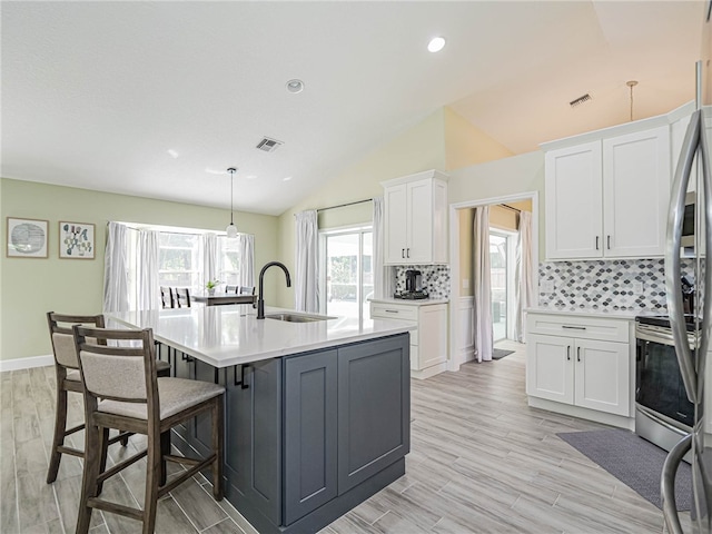 kitchen with white cabinets, sink, light hardwood / wood-style flooring, and lofted ceiling