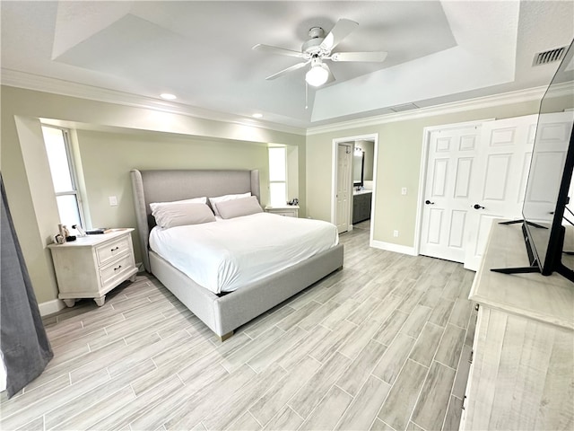 bedroom with multiple windows, light hardwood / wood-style flooring, ceiling fan, and a raised ceiling