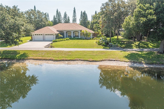 view of front of home with a garage, a water view, and a front lawn