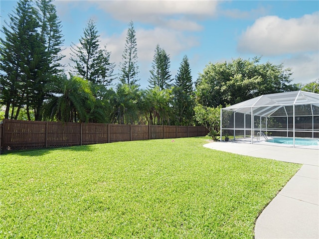 view of yard with a fenced in pool, glass enclosure, and a patio