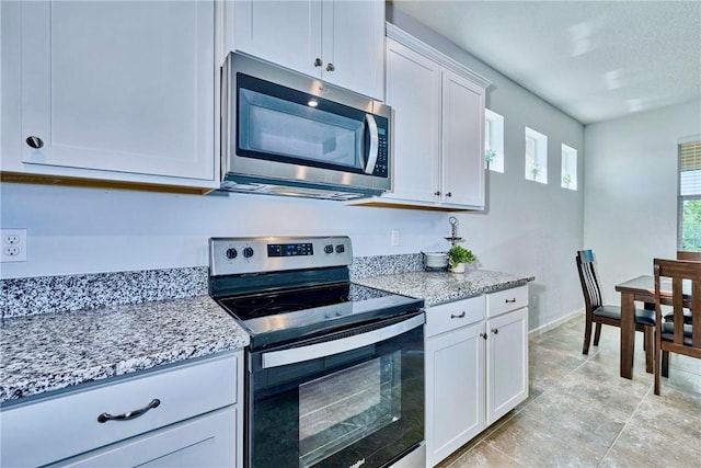 kitchen with baseboards, light stone countertops, appliances with stainless steel finishes, and white cabinets