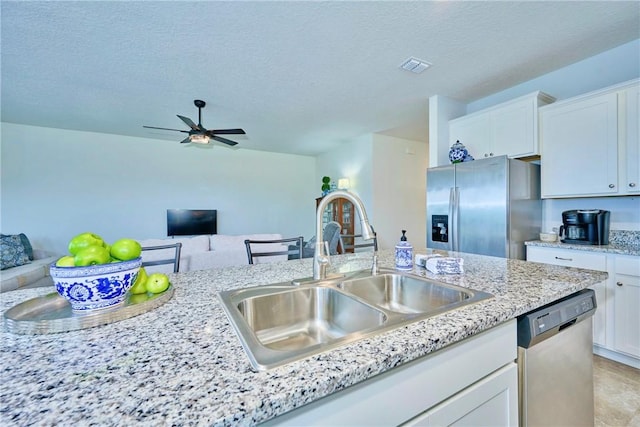 kitchen with visible vents, open floor plan, appliances with stainless steel finishes, white cabinets, and a sink