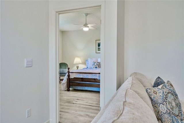 bedroom with a ceiling fan, wood finished floors, and a textured ceiling