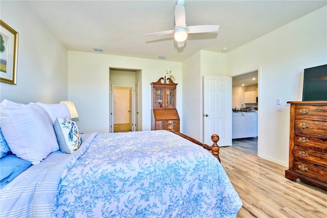 bedroom with visible vents, baseboards, wood finished floors, a textured ceiling, and a ceiling fan