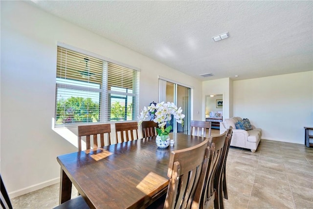 dining space with baseboards, visible vents, and a textured ceiling