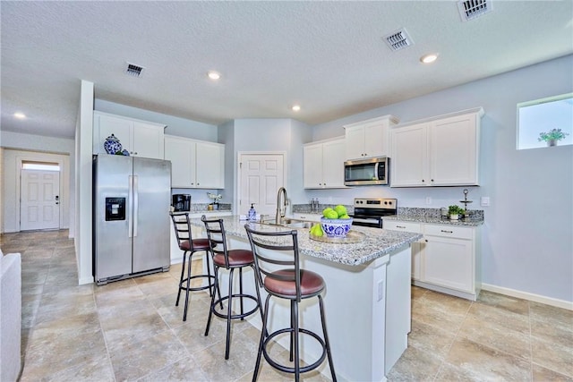 kitchen with a sink, visible vents, appliances with stainless steel finishes, and white cabinetry