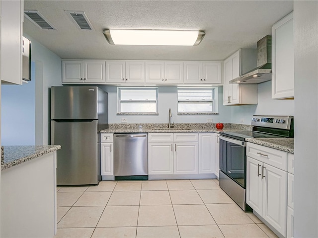 kitchen featuring stainless steel appliances, wall chimney range hood, white cabinetry, and sink