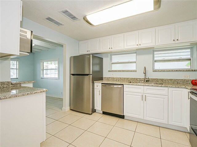 kitchen with white cabinetry, sink, appliances with stainless steel finishes, a textured ceiling, and light tile patterned floors