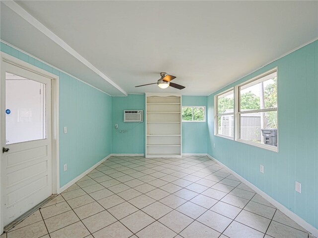 tiled empty room featuring an AC wall unit and ceiling fan