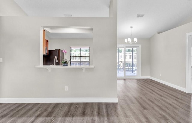 841 Carnation Dr, Sebastian, FL 32958 - unfurnished living room featuring baseboards, wood finished floors, healthy amount of natural light, and a chandelier
