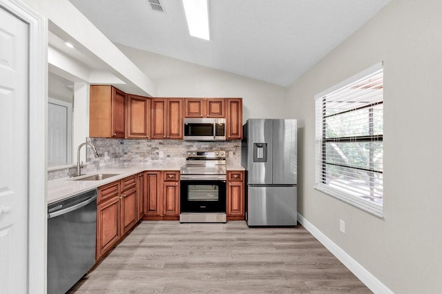 841 Carnation Dr, Sebastian, FL 32958 - kitchen featuring appliances with stainless steel finishes, a sink, brown cabinetry, backsplash, and vaulted ceiling