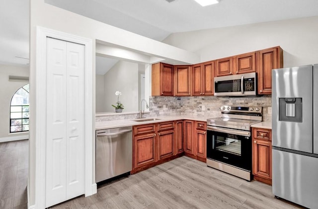 841 Carnation Dr, Sebastian, FL 32958 - kitchen with stainless steel appliances, a sink, light countertops, vaulted ceiling, and brown cabinetry