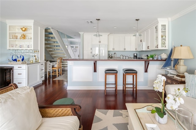 kitchen with crown molding, white appliances, white cabinetry, hanging light fixtures, and beverage cooler