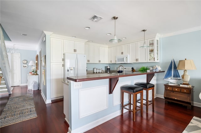 kitchen with dark hardwood / wood-style floors, crown molding, white appliances, hanging light fixtures, and white cabinets