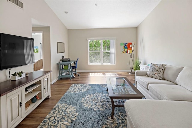 living area featuring dark wood-style flooring, baseboards, and vaulted ceiling