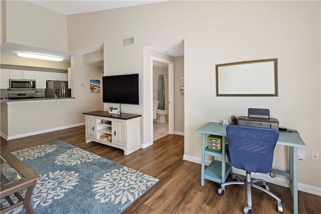 office with dark wood-style flooring, baseboards, and a towering ceiling