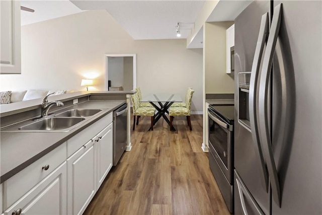 kitchen with appliances with stainless steel finishes, a sink, white cabinetry, and dark wood-style flooring